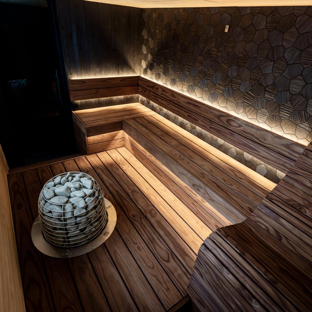 Moderne wellness-sauna i mørkt træ med stemningslys og stenovn — North Træbyg
